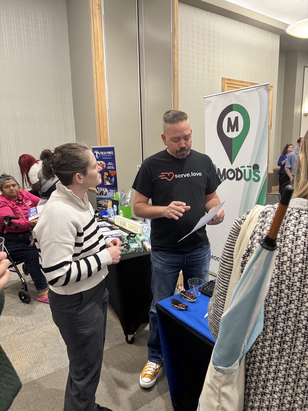 Justin at a Serve.Love community event booth talking with an attendee