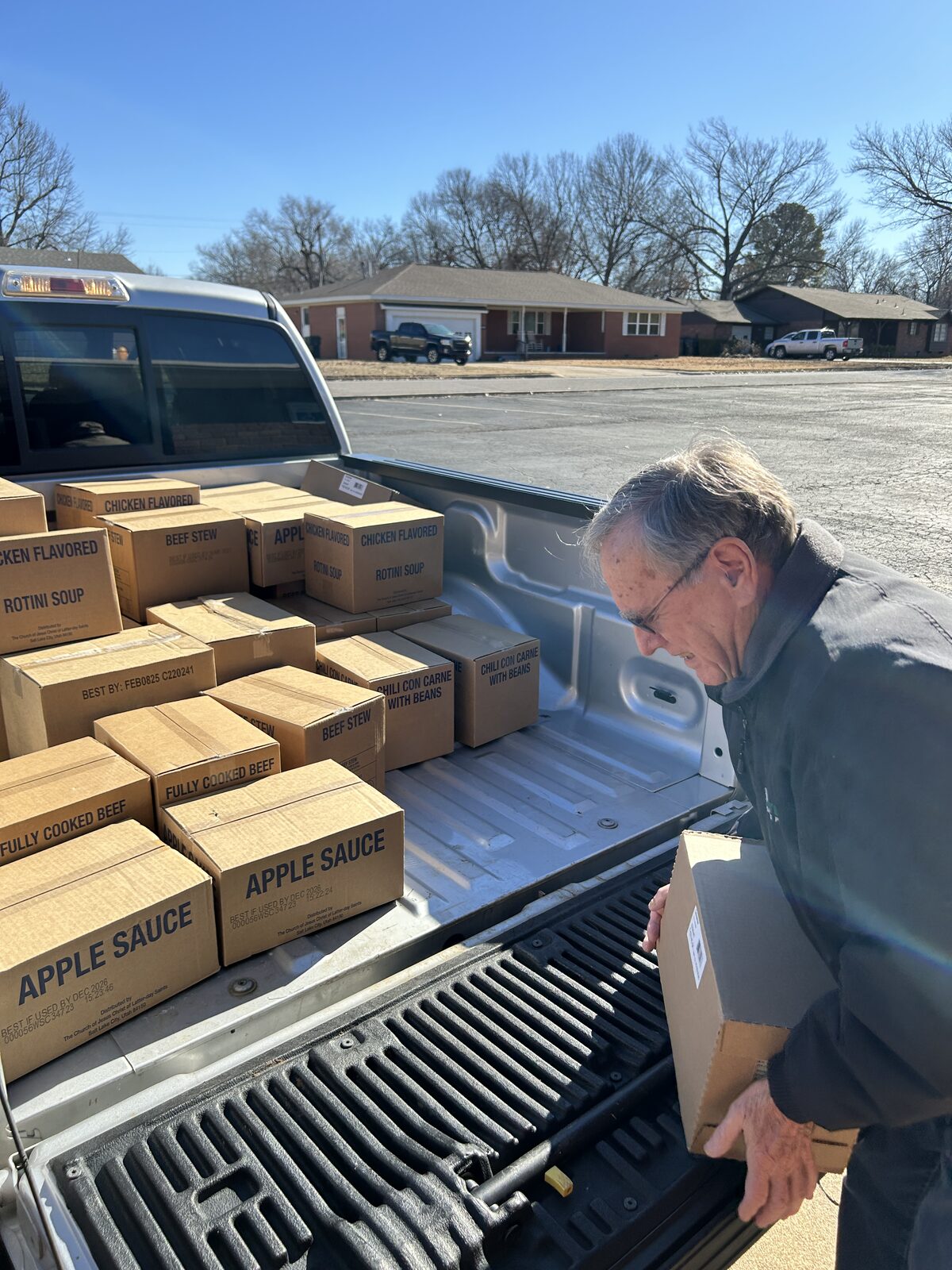 A volunteer unloads boxes of shelf-stable food from a pickup truck bed to restock the Blue Starr food pantry in Claremore, Oklahoma
