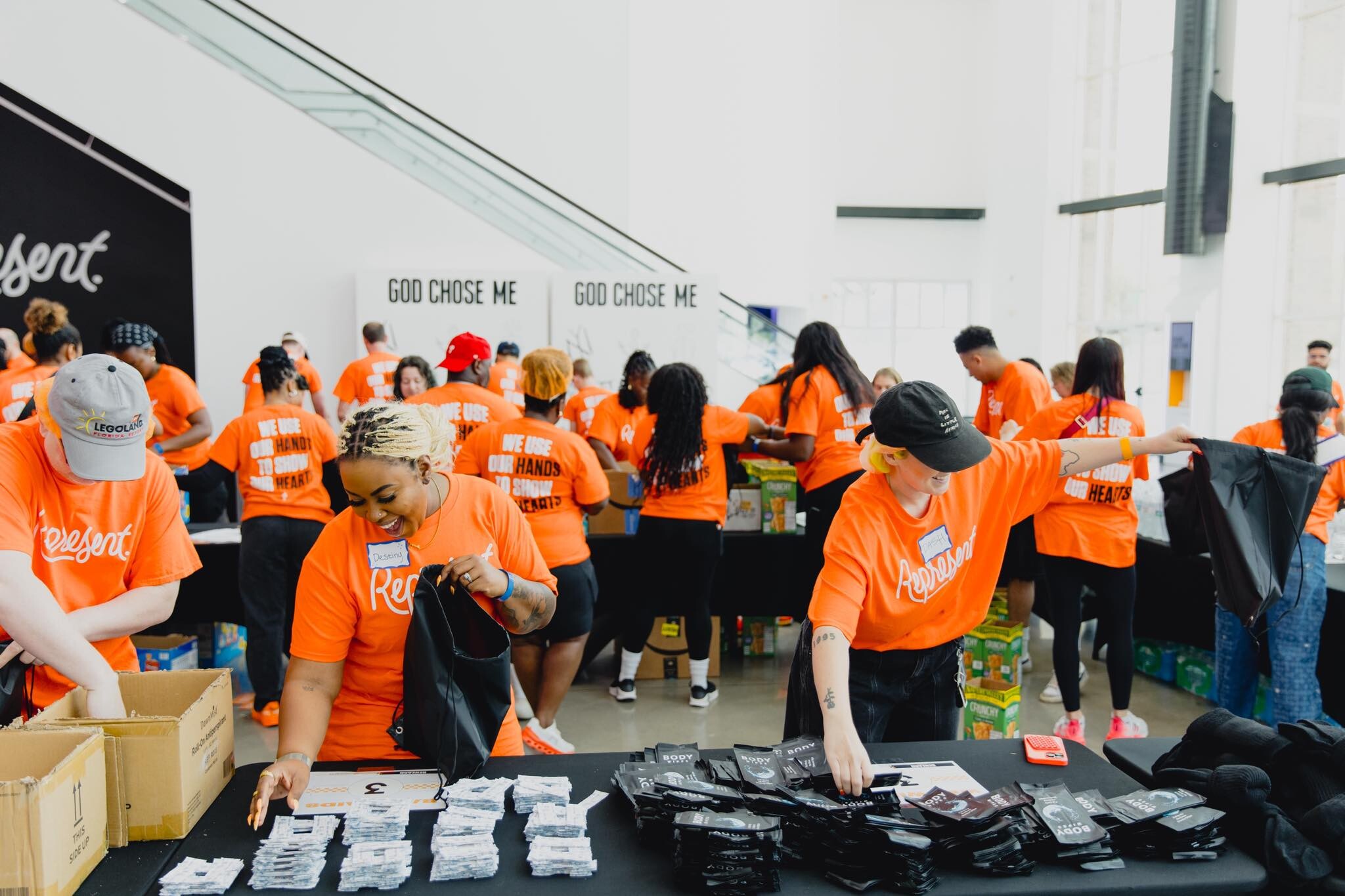 A large group of volunteers in orange shirts packing kits together at a community service event